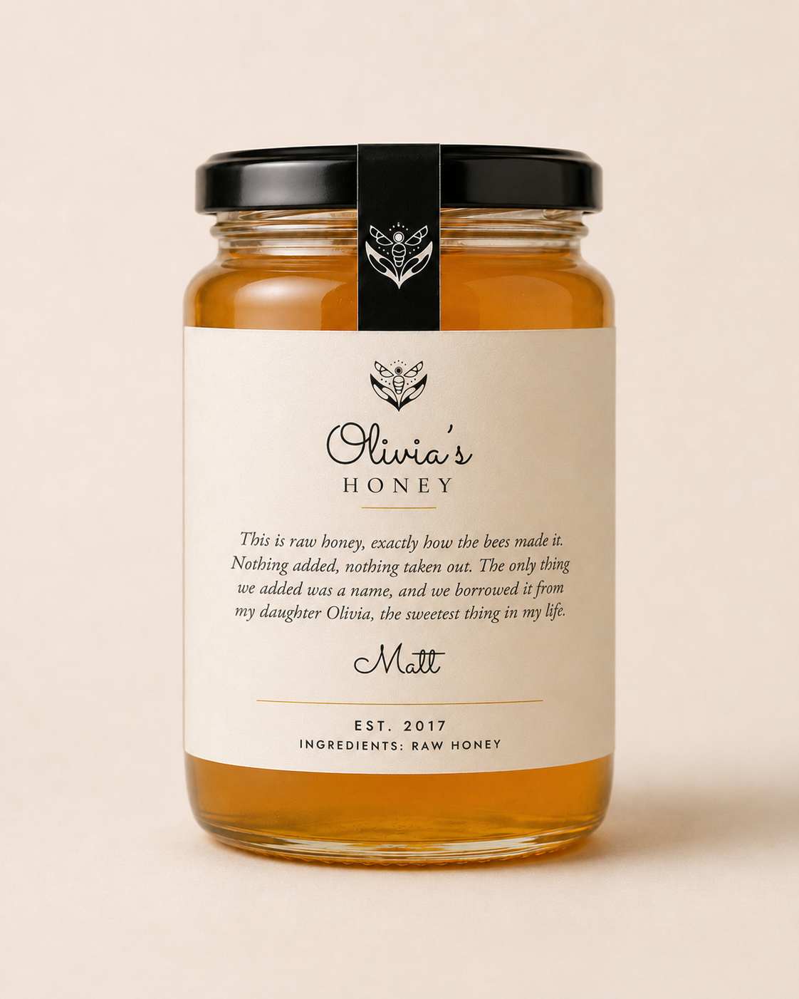 Jar of Olivia's Honey with a black lid on a beige background